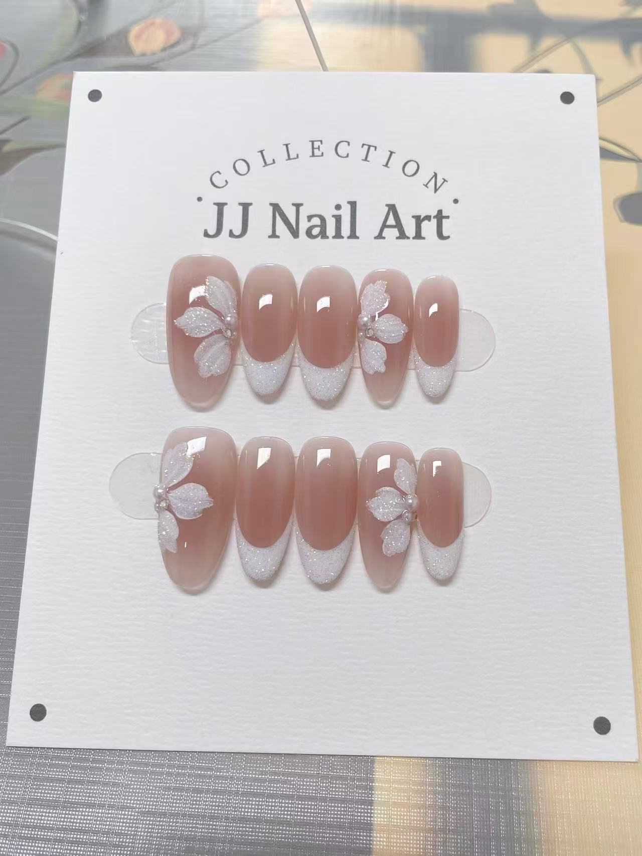 JJ Nail Art nail art collection on a white card with floral designs.