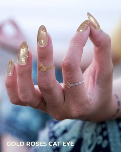 Hand with gold rose cat eye nail design and rings on a blurred background