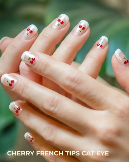Nails with cherry design and cat eye effect, set against a blurred green background.