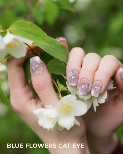 Hands with decorative nail art holding white flowers against a blurred green background