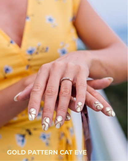 Close-up of hands with gold pattern cat eye nail design on a blurred background