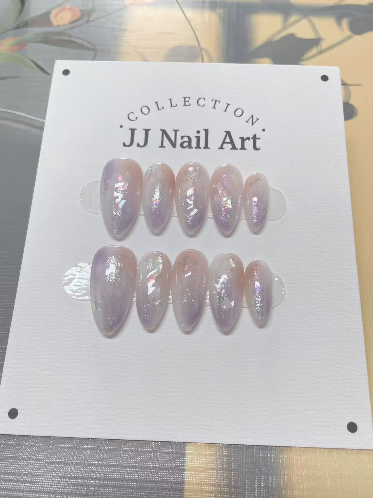JJ Nail Art nail extensions on a display card with a floral background.