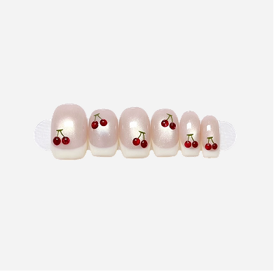 Set of pearl nail tips with cherry designs on a white background