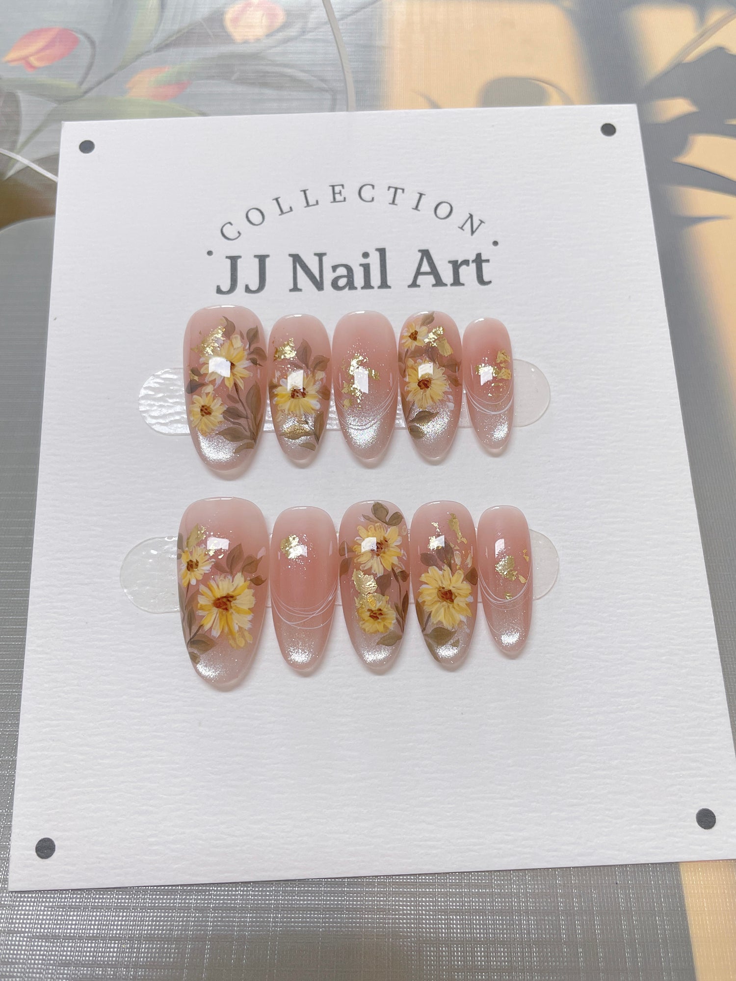 JJ Nail Art nail art display with floral designs on a white card.