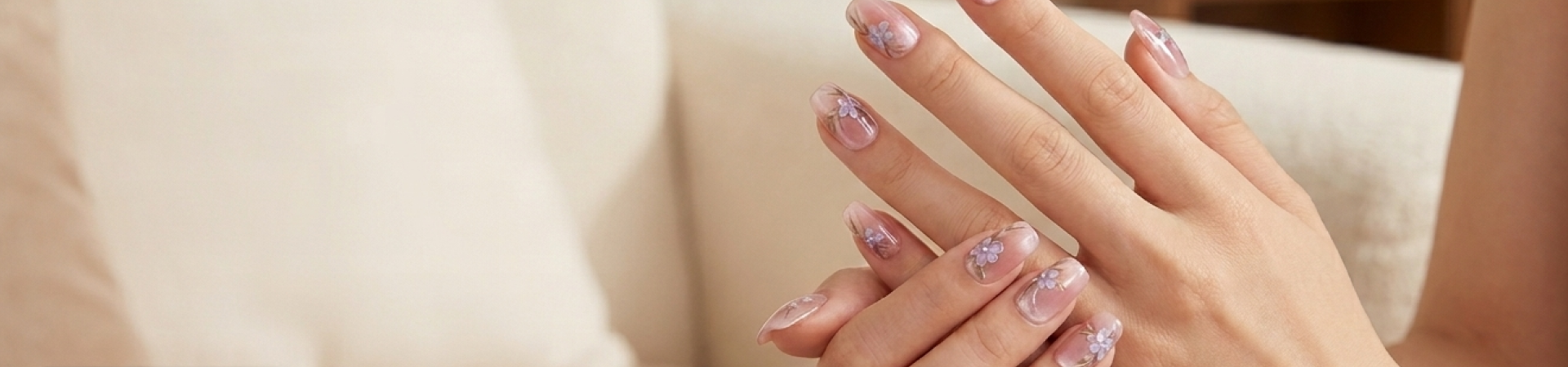Close-up of hands with decorative nail art on a neutral background