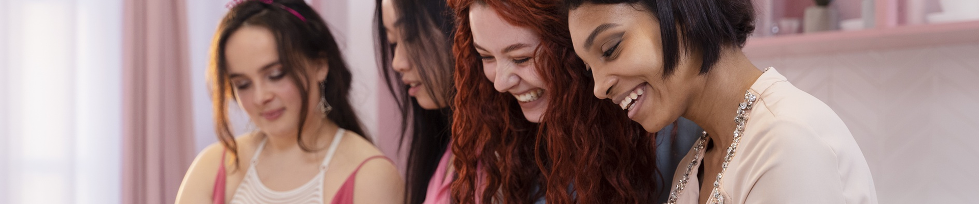 Three women sitting together, smiling and looking at something off-camera.