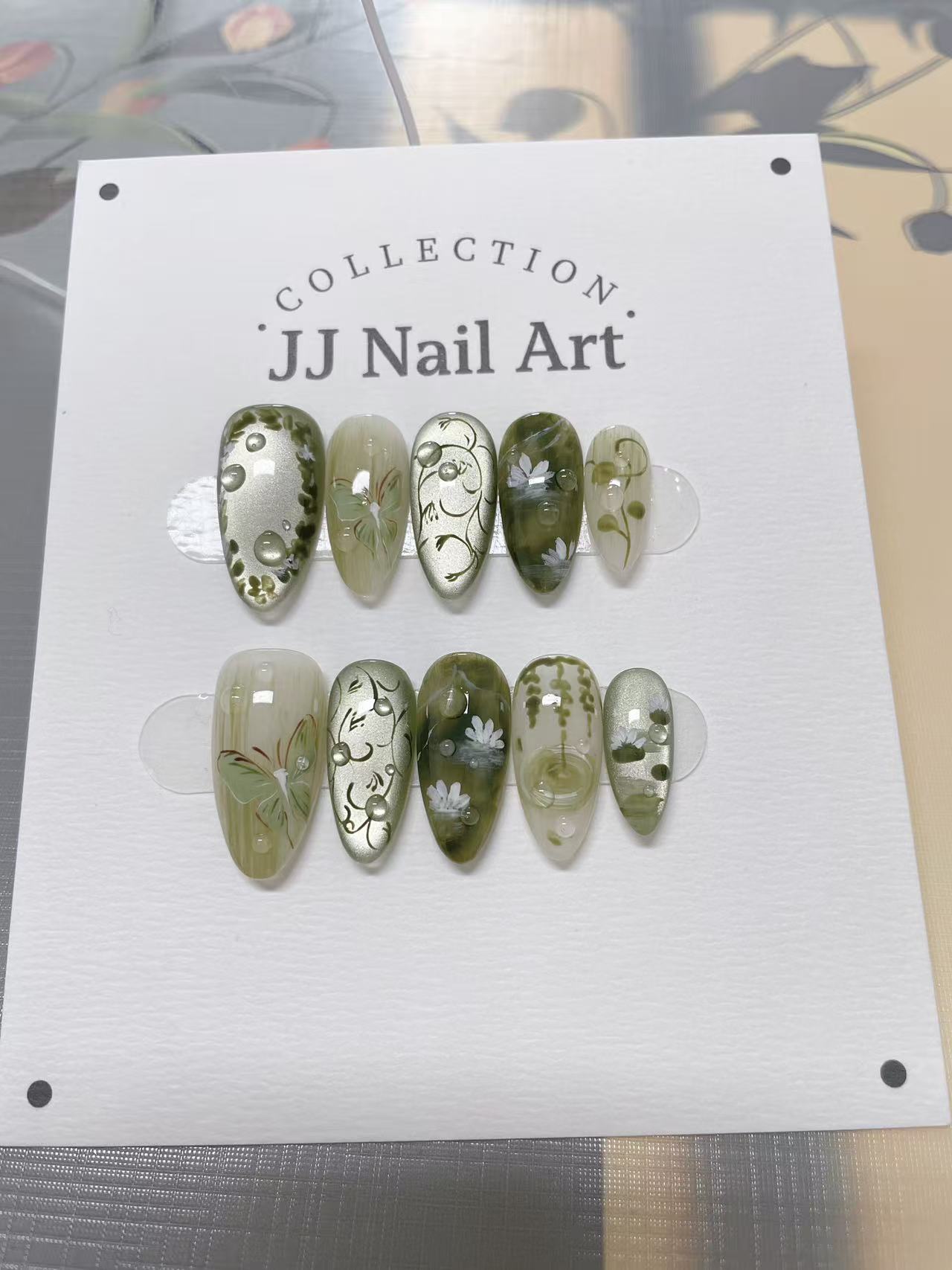 JJ Nail Art nail art collection on a display card with a blurred background
